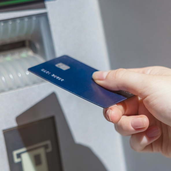 Dłoń wkładająca kartę do bankomatu